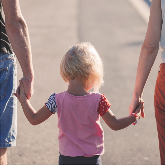 Criança de mãos dadas com o pai e com a mãe